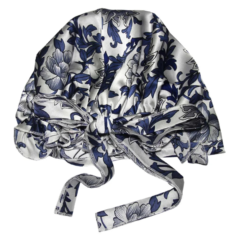 Blue and grey floral satin bonnet with a bow, designed for luxurious hair protection during sleep, featuring an elegant floral print on satin fabric.